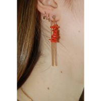 Boucles d'oreilles upcyclées ornées de coraux rouges portées à une oreille.