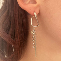 Photo portée de la première boucle entièrement en argent. Elle est composée d'une créole torsadée en argent, à laquelle sont suspendues deux chaînes vintages en argent.