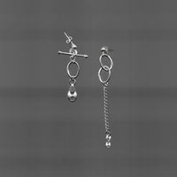 Ces boucles d'oreilles upcyclées asymétriques en argent 925 se distinguent par une chaîne pendante, tandis que l'autre présente une pierre en suspension.