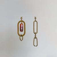 Les boucles d'oreilles uniques sont suspendues devant un fond blanc.