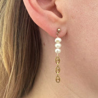 Photo portée d'une boucle d'oreille upcyclée pendante, avec une moitié de perles d'eau douce et une autre moitié en chaîne grain de café plaquée or vintage.