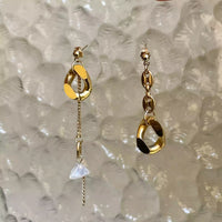 Les boucles d'oreilles Tête d'Orange sont suspendues pour qu'on voit les détails des éléments vintages qui forment cette boucle. Un maillon pour chaque boucle, une chaîne pendante pour l'une d'elle et des grains de cafés dispersés.