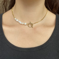 Ce collier upcyclé, réalisé avec des chaînes vintages plaquées or et des perles d'eau douce.