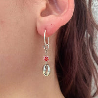 La deuxième boucle portée, avec de haut en bas : créole en argent, fermoir décoratif en argent, perle rose avec motif de fleur rouge, puis un grand grain de café argent.