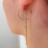Photo portée d'une des boucles d'oreilles unique Tête d'Orange. On voit une créole plaquée or coupée à la moitié, attachée à l'oreille avec un fermoir papillon. Sur ce fermoir sont attachées deux chaînes, une en argent et une fine en plaqué or.