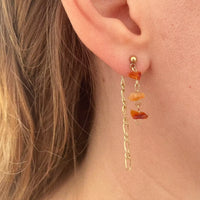 Une des boucles d'oreilles portée par notre modèle. à l'avant, trois cornalines suspendues au fermoir, et à l'arrière de ce dernier, accroché à lui, une longue chaîne fine plaquée or