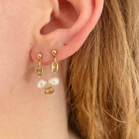 Photo portée d'une boucle d'oreille unique Tête d'Orange. Elle s'attache sur deux trous de l'oreille, et est composée de trois grains de café séparés chacun d'une perle d'eau douce vintage.