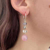 La première boucle portée. Elle se compose, du haut vers le bas : d'une créole fine en argent, d'une perle bleue nuit transparente, d'un grain de café argent, d'un élélement rectangulaire en résine transparent, et d'une grosse perle rose.