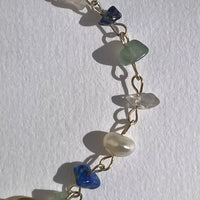 Zoom sur la monobouble, et noamment les pierres précieuses. Du fermoir de lobe jusqu'à la bague d'oreille, nous avons, un quartz transparent, une lapis-lazuli, un quartz vert, un quartz transparent, une perle d'eau douce, une lapis-lazuli, et encore un quartz vert.