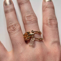 Photo en gros plan d'une main qui porte la bague upcyclée Issey. On voit en détail les chaînes fines figaro qui suivent la largeur de la chaîne grain de riz plaquée or.