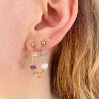 Une des boucles portée sur l'oreille. C'est une pièce très colorée qui s'attache sur deux trous du lobe, elle est composée uniquement de pierres semi-précieuses, reliées ensemble par des tiges plaquées or.