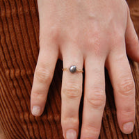 Bague upcyclée ornée d'une perle d'eau douce noire portée au doigt