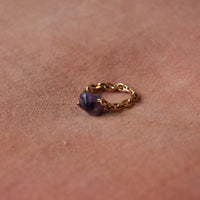 Bague upcyclée ornée d'une améthyste posée sur un fond rose