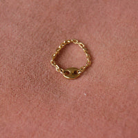Bague upcyclée grain de café plaqué or posée sur un tissus vieux rose