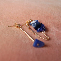 Boucles d'oreilles upcyclées ornées de lapis lazulis posées sur un tissu rose.