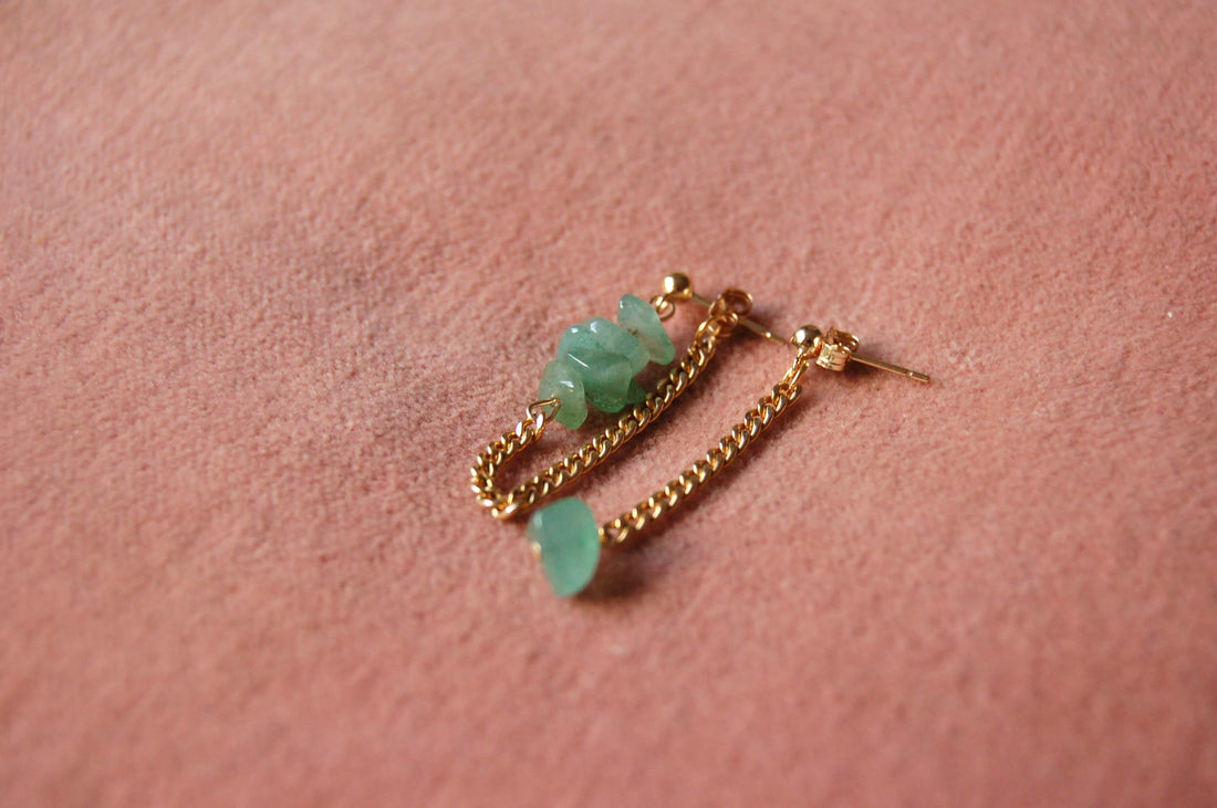 Boucles d'oreilles upcyclées ornées de quartz  verts posées sur un tissu rose.