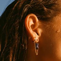 Boucles d'oreilles upcyclées ornées de lapis lazulis portées à une oreille.