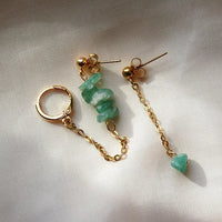 Boucles d'oreilles upcyclées ornées de quartz verts posées sur un tissu clair.