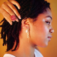 Boucles d'oreilles upcyclées ornées de chaînes et d'une grosse perle d'eau douce portées à une oreille.