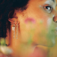 Boucles d'oreilles upcyclées ornées de chaînes et d'une grosse perle d'eau douce portées à une oreille.