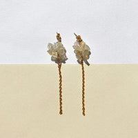 Boucles d'oreilles upcyclées ornées d'une chaîne et de citrines posées sur un fond clair bicolore.