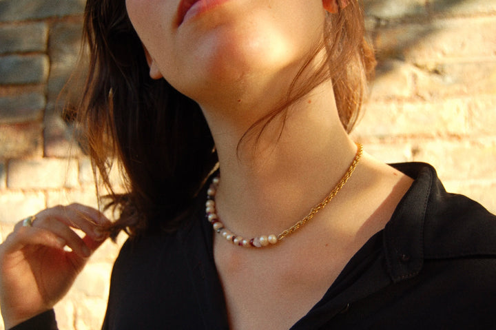 Isabelle porte un collier upcyclé tête d’orange, mi perles mi chaîne dorée.