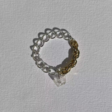 La bague upcyclée Spring, une bague asymétrique composée de deux chaînes chinées en argent et plaquée or. Ornée d'un quartz blanc.