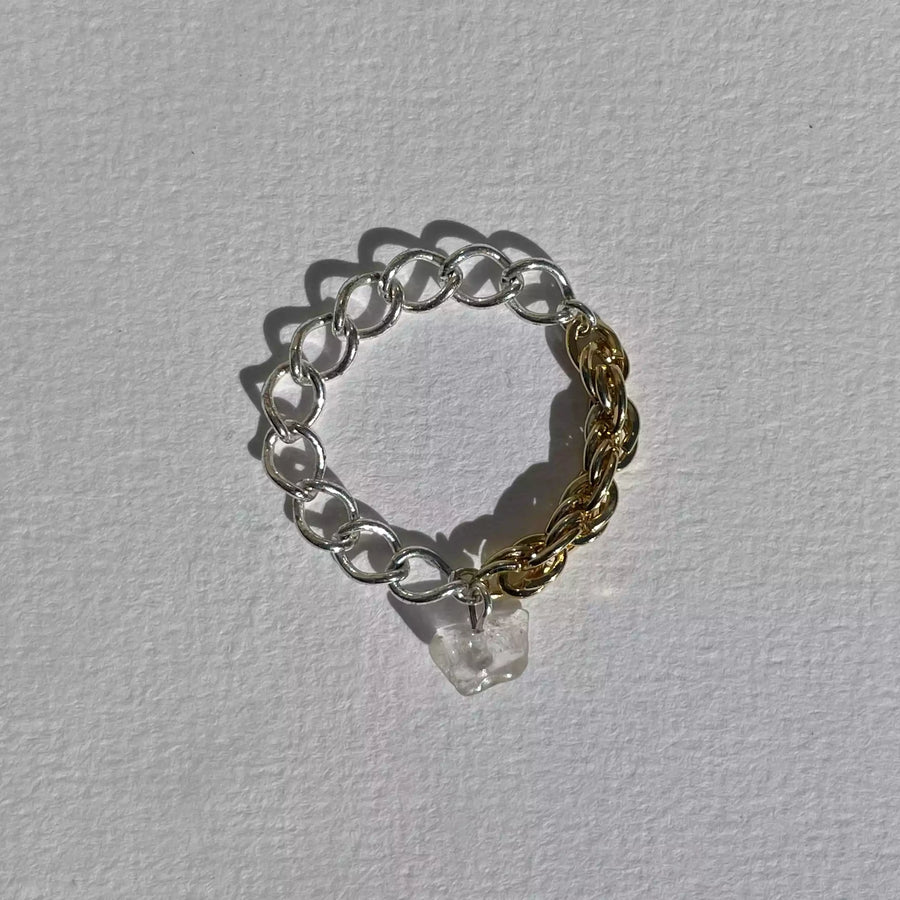 La bague upcyclée Spring, une bague asymétrique composée de deux chaînes chinées en argent et plaquée or. Ornée d'un quartz blanc.