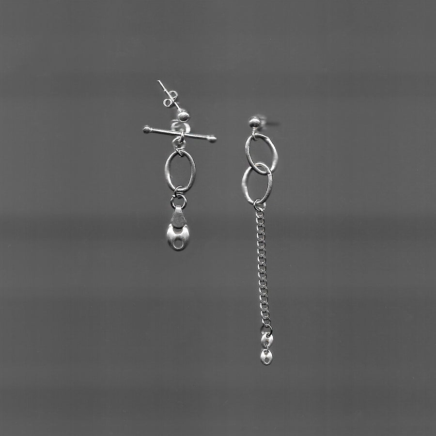 Ces boucles d'oreilles upcyclées asymétriques en argent 925 se distinguent par une chaîne pendante, tandis que l'autre présente une pierre en suspension.