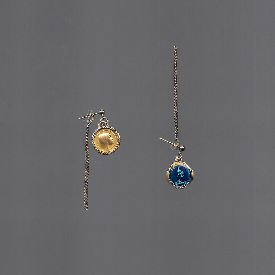 Ces boucles d'oreilles upcyclées pendantes sont en plaqué or et ornées de médailles religieuses, l'une en plaqué or et l'autre en émail bleu.