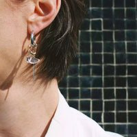 Photo d'une modèle qui porte une des deux boucles d'oreilles. La personne tourne un peu la tête pour quon voit le côté de la créole argent.