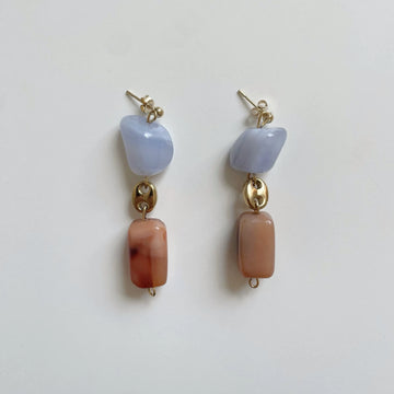 La paire de boucles d'oreilles unique posée sur fond blanc.