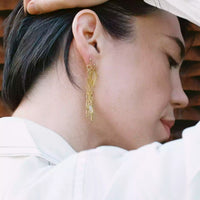 Photo de notre modèle qui porte une des deux boucles sur la même oreille. On remarque que le plaqué or attire particulièrement la lumière, ainsi que les pierres jaunes.