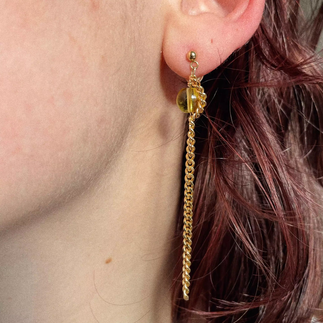 Le modèle porte la deuxième boucle d'oreille, c'est une perle jaune avec la chaîne plaquée or qui l'entoure et qui retombe pour être de la même longueur que la première boucle.