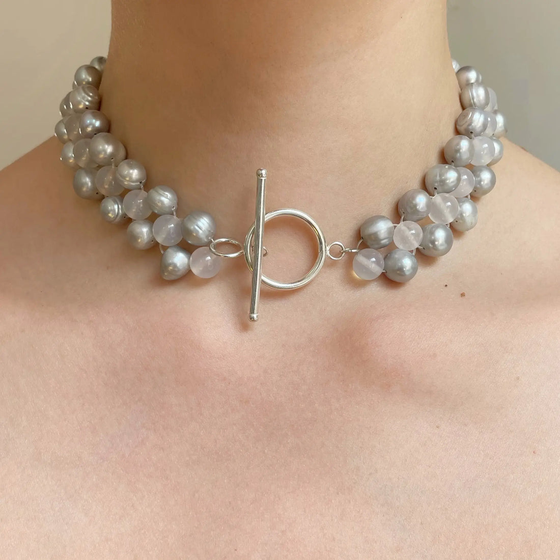 On voit le collier porté au cou de la modèle, avec le joli tissage de perle fait main qui entoure délicatement le cou.