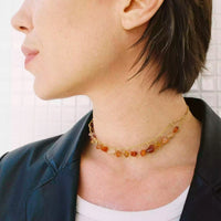 Photo de la modèle qui porte le collier upcyclé Sezny. Il est composé de deux chaînes plaquées or qui longent le cou. Entre elles, et sur toutes leur longueur, sont accrochées des cornalines.