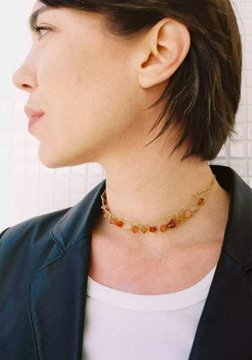 Photo de la modèle qui porte le collier upcyclé Sezny. Il est composé de deux chaînes plaquées or qui longent le cou. Entre elles, et sur toutes leur longueur, sont accrochées des cornalines.