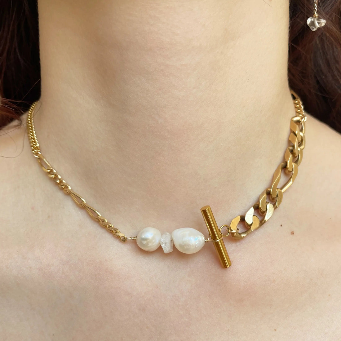 Le collier est porté au cou de la modèle. Les perles sont au centre du collier et les différentes chaînes vintages s'alternent harmonieusement.