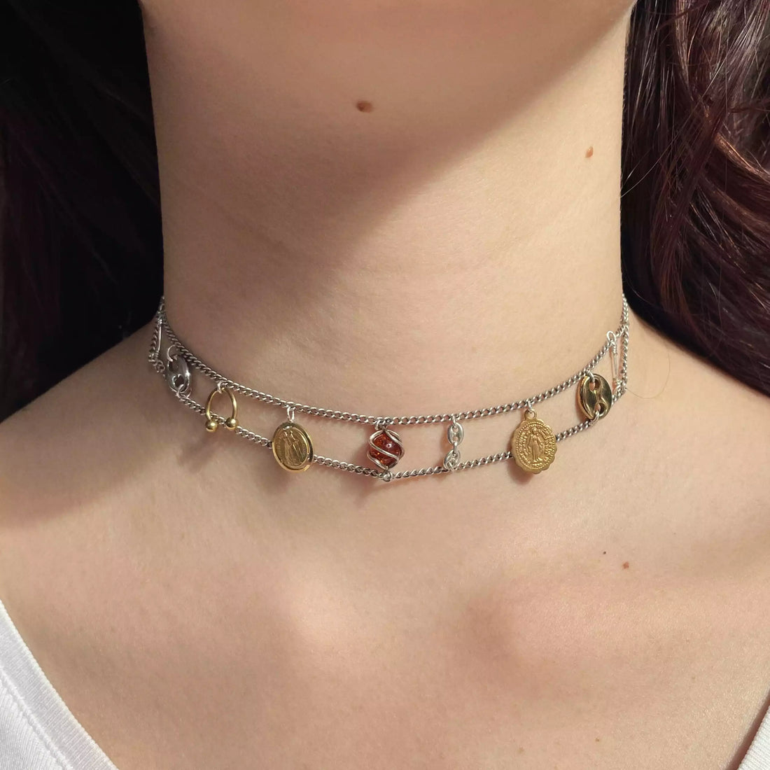Le collier unique Tête d'Orange porté sur un cou. On voit les différents médaillons plaqués or, argent qui sont disposés entre deux chaînes fines en argent.
