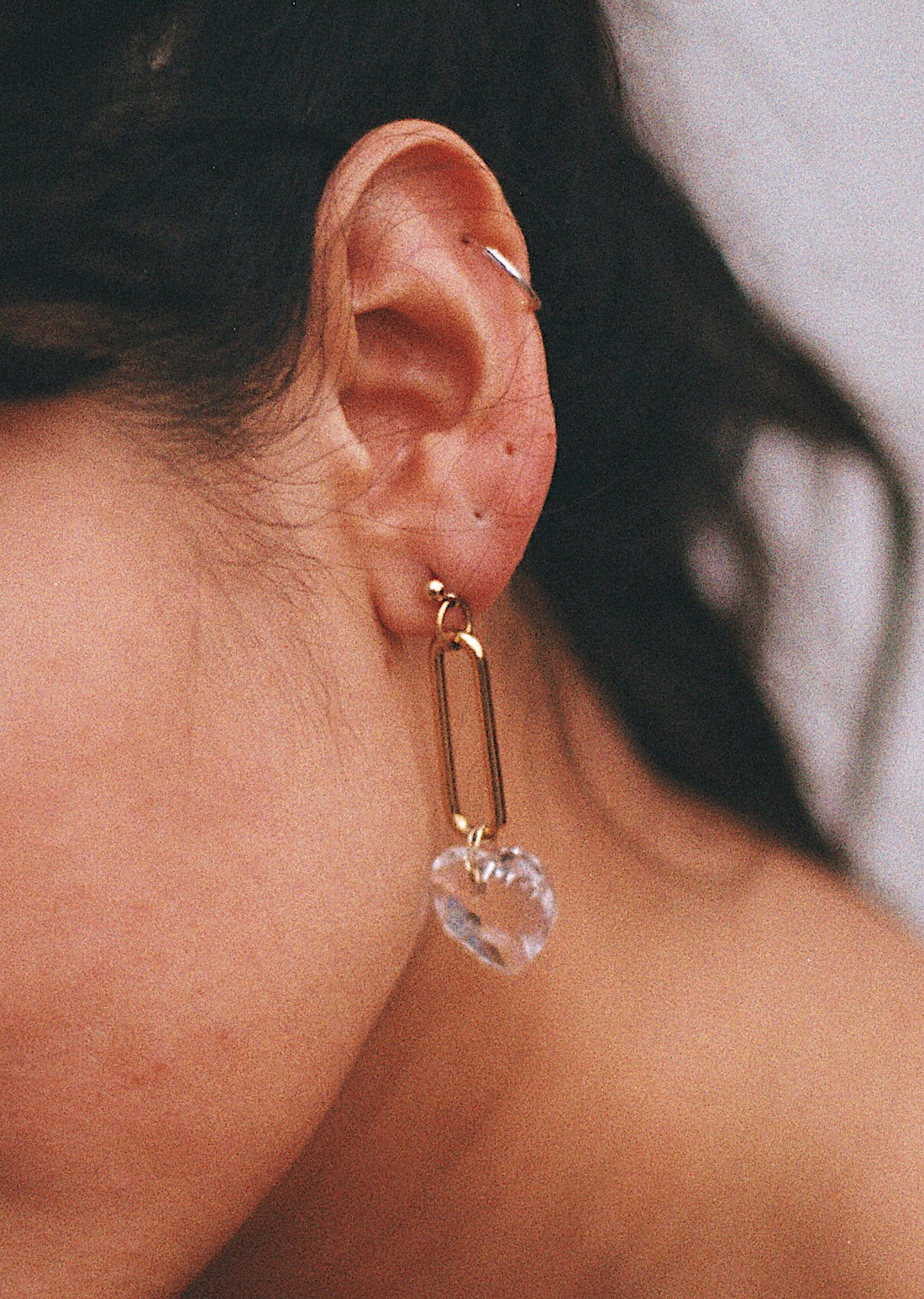 La boucle d'oreille upcyclée composée d'un coeur et d'un maillon vintage est portée par la modèle à son oreille.