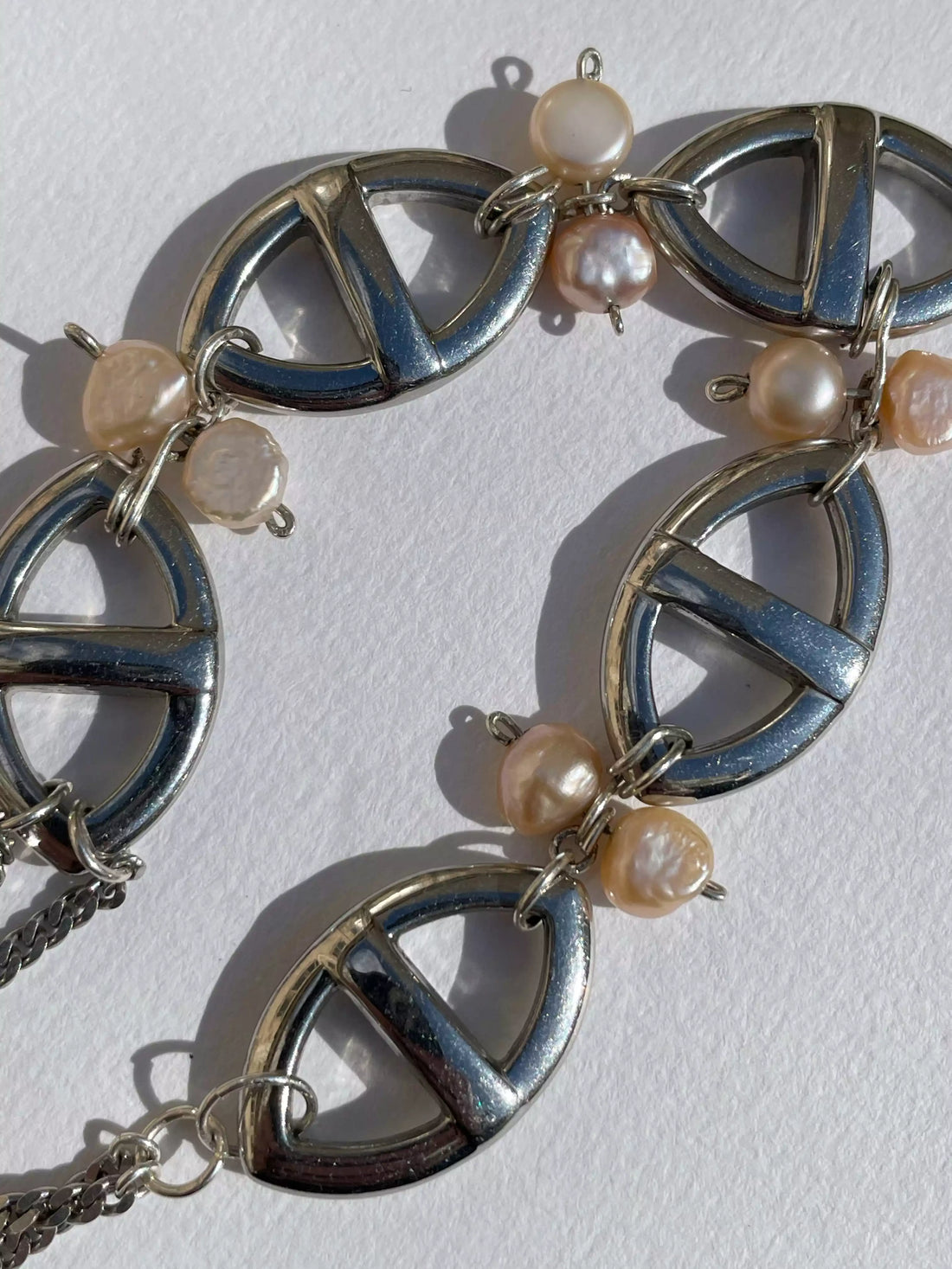Gros plan des détails du collier fait main. On voit l'assemblage des perles d'eau douce sur les maillons marines en argent.