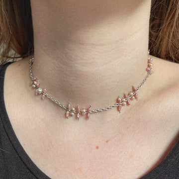 La modèle porte le collier unique upcyclé Saba. Nous voyons de près l'assemblage des petites perles allongées roses et des petites perles d'eau douce blanche sur la chaîne en argent.
