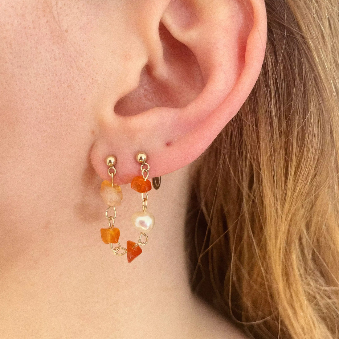 cette boucle d'oreille est composée de plusieurs cornalines avec differentes teintes d'orange, et une perle d'eau douce. Lalliance de ces éléments forme une chaîne qui fait le lien entre les deux trous du lobe.