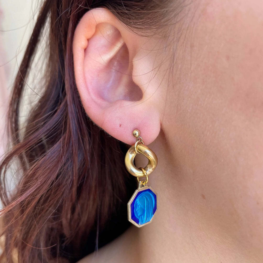 La première boucle portée à l'oreille. elle est composée d'un maillon plaqé or et d'une médaille bleue 