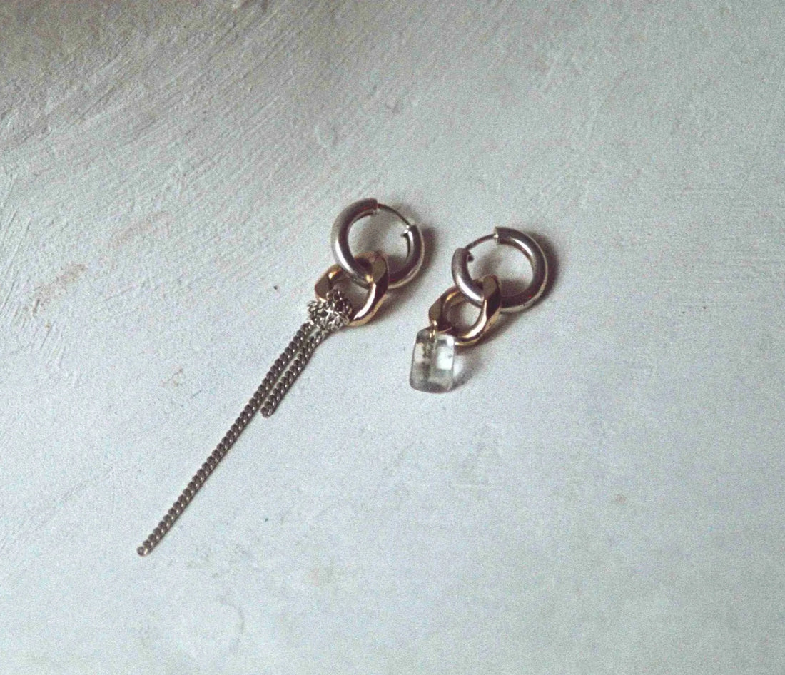 la paire de boucles d'oreilles unique posée sur fond blanc. On voit l'asymétrie tendance sur cette création.