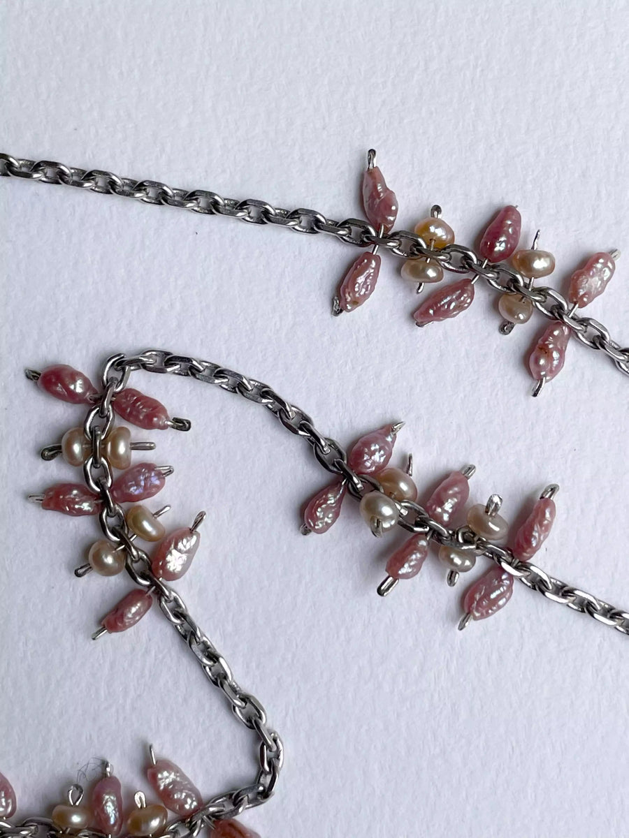 Photo en gros plan de la chaîne en argent chinée à Strasbourg qui compose le collier, et l'attache des perles sur cette chaîne, qui forme un ensemble au style fleuri.