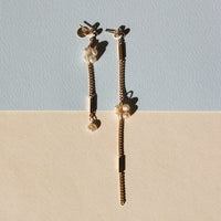 Boucles d'oreilles upcyclées ornées de perles d'eau douce et de chaînes en plaqué or posées sur un fond bicolore coloré. 