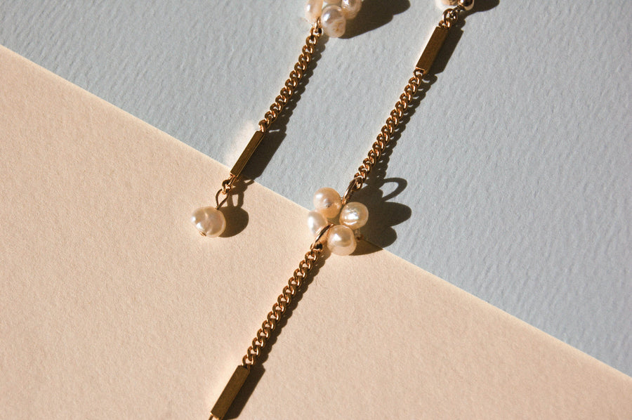 Boucles d'oreilles upcyclées ornées de perles d'eau douce et de chaînes en plaqué or posées sur un fond bicolore coloré. 