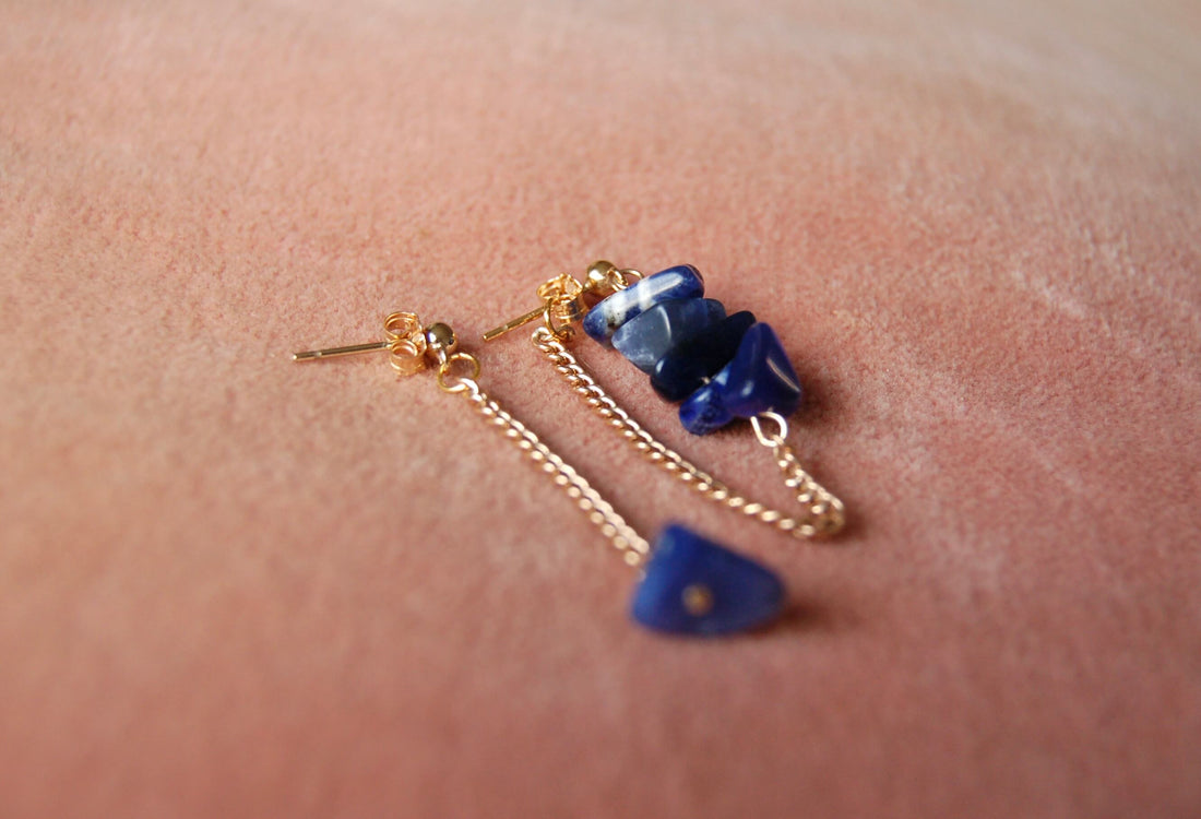 Boucles d'oreilles upcyclées ornées de lapis lazulis posées sur un tissu rose. 