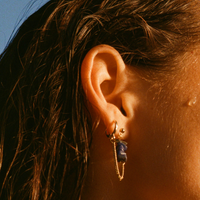 Boucles d'oreilles upcyclées ornées de lapis lazulis portées à une oreille. 